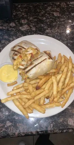 A grilled wrap with french fries and a dipping sauce on a white plate