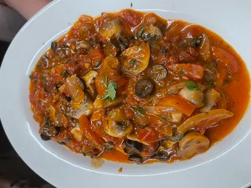 Mushrooms, black olives and peppers in tomato sauce on an oval plate