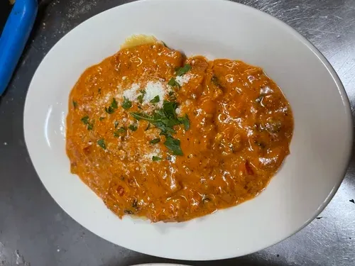 Pasta in a creamy tomato sauce with grated cheese and parsley on an oval plate