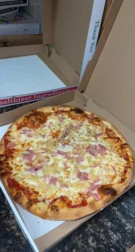 A ham and cheese pizza in an open takeout box