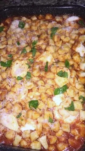 Baked gnocchi in tomato sauce with melted cheese and basil