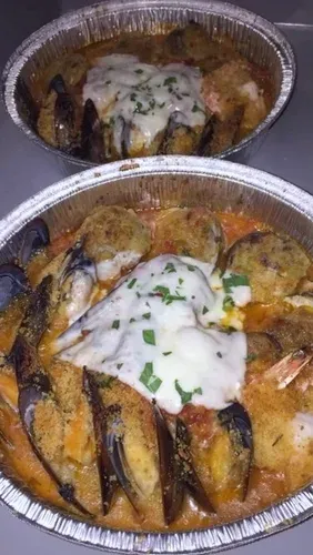 Baked mussels and stuffed clams in red sauce under melted cheese, in two foil trays