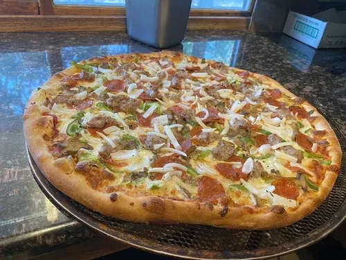A supreme pizza with sausage, pepperoni, green peppers and onions on a pan