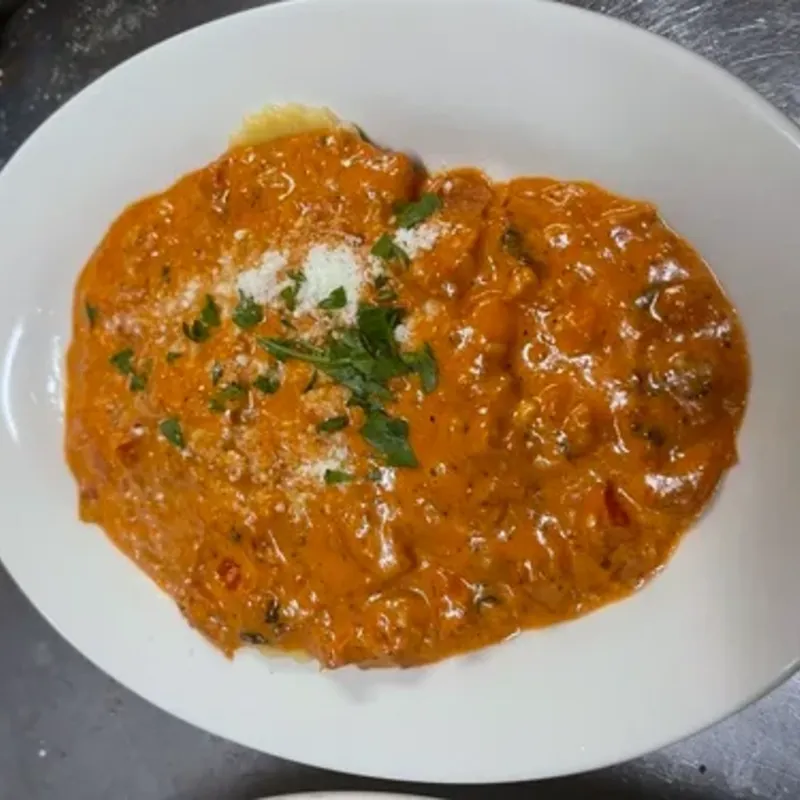 Pasta in a creamy tomato sauce with grated cheese and parsley on an oval plate
