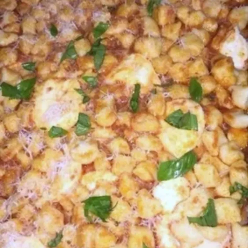 Baked gnocchi in tomato sauce with melted cheese and basil