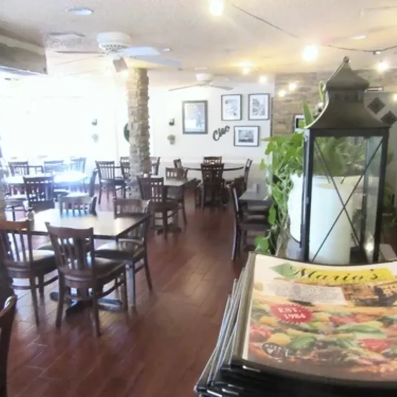 The dining room, with stone pillars, wood tables and chairs and string lights, and a stack of menus in the foreground