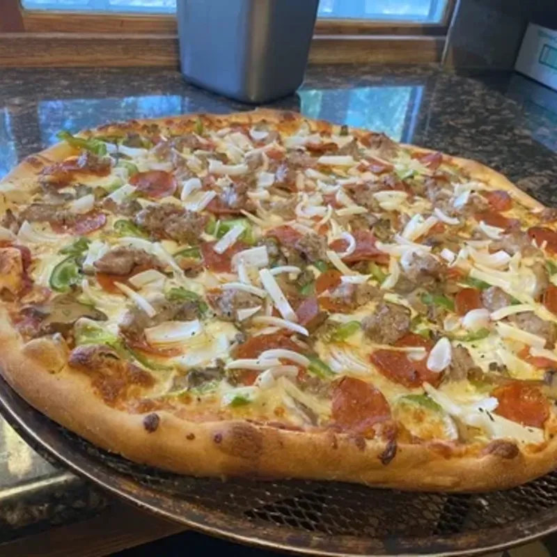 A supreme pizza with sausage, pepperoni, green peppers and onions on a pan